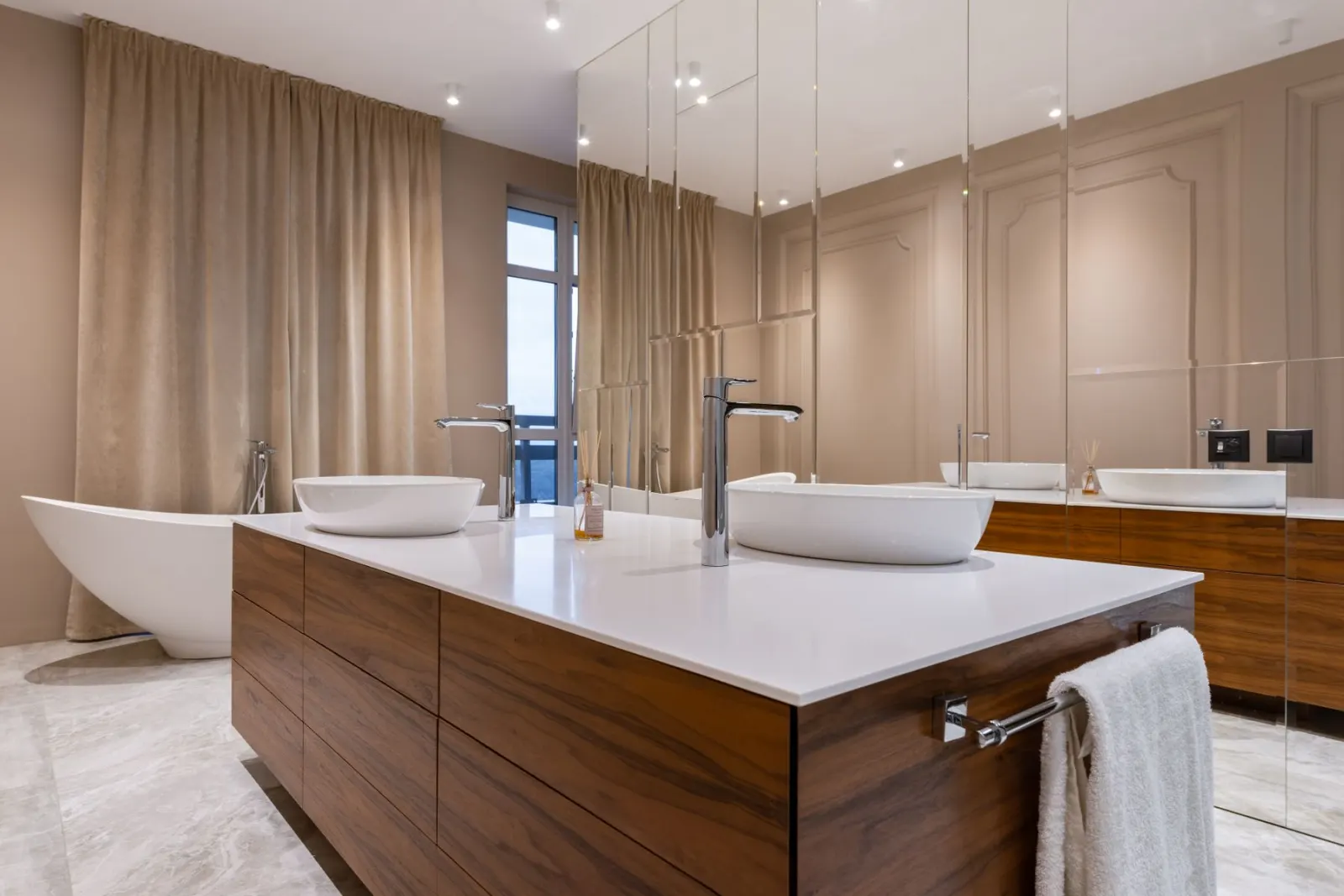 A finished bathroom with a bath, twin basins and tiling